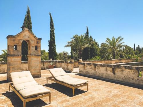 two lounge chairs on a patio with palm trees at Masseria Marzalossa in Fasano