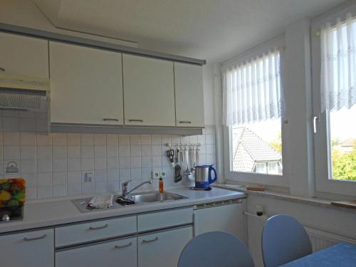 eine Küche mit weißen Schränken, einem Waschbecken und einem Fenster in der Unterkunft Ferienhaus "Heißer Sand", Whg 7 in Wittdün