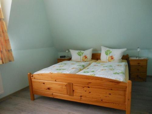 1 dormitorio con 1 cama de madera y 2 almohadas en Ferienhaus-Heisser-Sand-Whg-7, en Wittdün