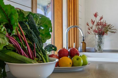 a bowl of vegetables on a counter with apples and oranges at Manfield Country Bruny Island in Alonnah