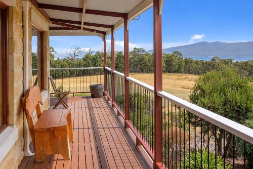 a porch with a bench and a view of a field at Manfield Country Bruny Island in Alonnah