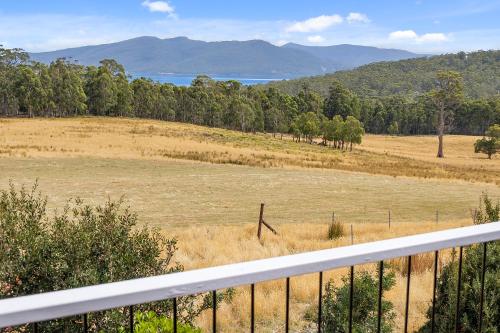 a view of a field with a fence and trees at Manfield Country Bruny Island in Alonnah