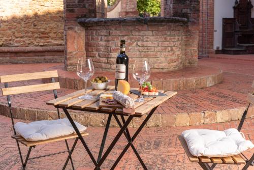 a table with a bottle of wine and two glasses at Borgo San Lorenzo a Linari in San Rocco a Pilli