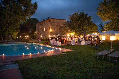 un grupo de personas de pie alrededor de una piscina por la noche en Borgo San Lorenzo a Linari, en San Rocco a Pilli