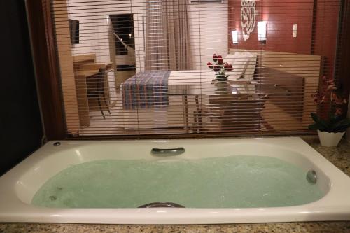 a bath tub with a view of a bedroom at Hotel Pousada do Sol in Aracaju