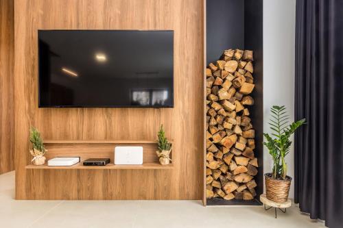 a television on a wall with a pile of wood at Zerm Holiday House with pool, jacuzzi & sauna - Gorski kotar in Mrkopalj