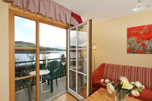 a living room with a couch and a table and a balcony at Hotel Garni Dorferwirt am Irrsee in Tiefgraben