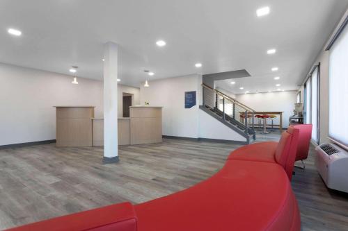 a living room with a red couch and a staircase at Travelodge by Wyndham Elkhart in Elkhart