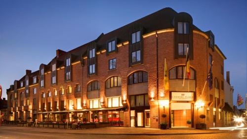 ein großes Backsteingebäude in der Nacht auf einer Straße in der Unterkunft Crowne Plaza Hotel Brugge, an IHG Hotel in Brügge