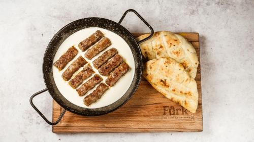 a frying pan with bacon and bread on a cutting board at Royal Airport Hotel in Velika Gorica
