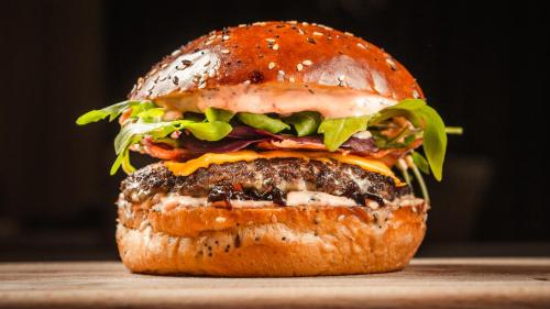 a hamburger with cheese and lettuce on a bun at Royal Airport Hotel in Velika Gorica