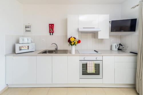 a kitchen with white cabinets and a sink at Spileo House Boutique Apartments - Adults Only in Mesongi