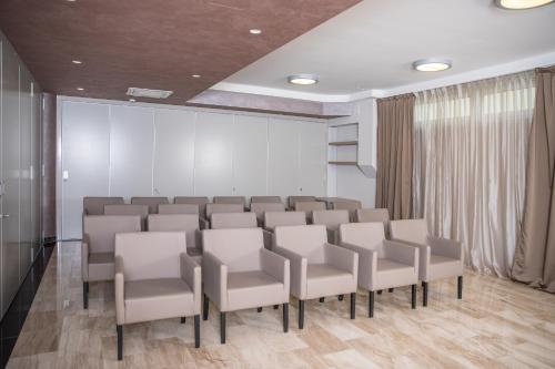 a conference room with white chairs and a wall at Royal Airport Hotel in Velika Gorica