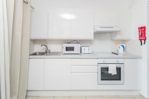 a white kitchen with a sink and a microwave at Spileo House Boutique Apartments - Adults Only in Mesongi