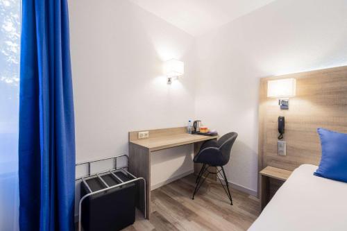 a hotel room with a desk and a bed at Hotel Le Circuit Le Mans in Le Mans