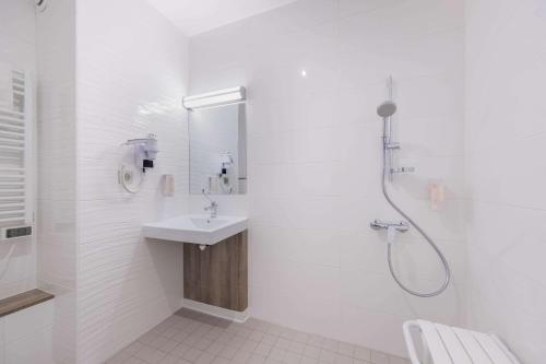 a white bathroom with a sink and a shower at Hotel Le Circuit Le Mans in Le Mans