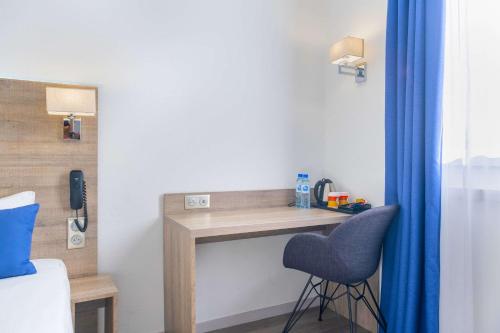 a desk in a bedroom with a blue chair at Hotel Le Circuit Le Mans in Le Mans