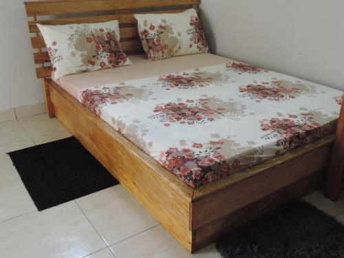 a bed with a wooden frame with flowers on it at HAPPY WELCOME Biétry 3 - MARCORY ZONE 4 in Abidjan