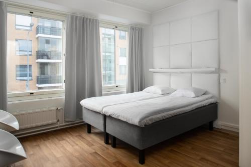 a white bedroom with a bed and a window at Omena Hotel Pori in Pori