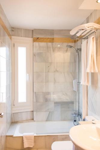 a bathroom with a tub and a sink at Sagitario Hostal Ciutadella in Ciutadella