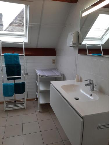 a white bathroom with a sink and a window at Huis Pimpernel in Bredene