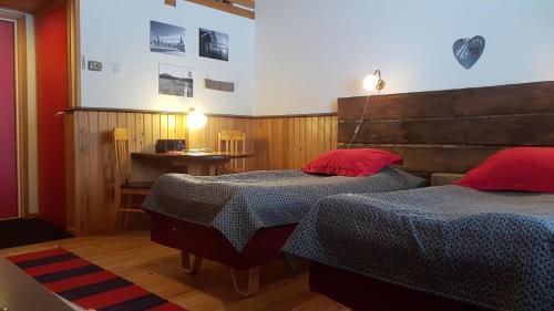 a bedroom with two beds and a table with a lamp at Hotel Seita in Äkäslompolo