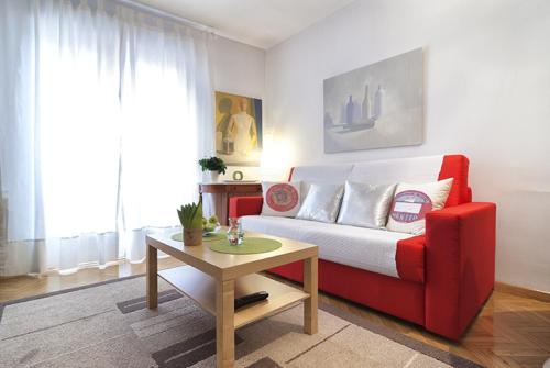 sala de estar con sofá rojo y mesa en MIT House Chueca X en Madrid, en Madrid