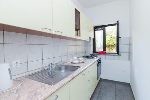 eine weiße Küche mit einem Waschbecken und einem Fenster in der Unterkunft Apartment Green Pag in Pag