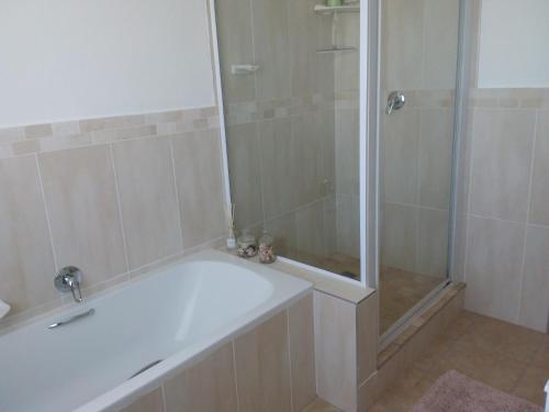 a bathroom with a shower and a white bath tub at Trev's Place in St Francis Bay