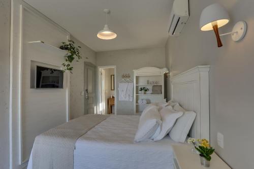 a white bedroom with a bed with white pillows at Solar Beach Hotel in Florianópolis