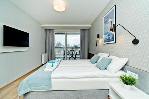 a bedroom with a large bed and a tv at BlueApart Apartamenty Na Klifie in Władysławowo