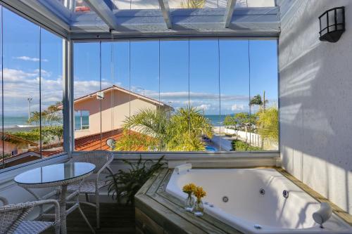 a bath tub in a room with a view of the ocean at Solar Beach Hotel in Florianópolis