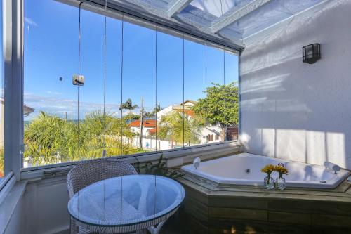 a bathroom with a tub and a chair and a window at Solar Beach Hotel in Florianópolis
