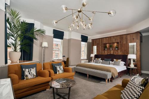 Hotel du Vin Birmingham في برمنغهام: غرفة نوم بسرير وكرسيين واريكة