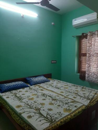 a bed in a bedroom with green walls and a ceiling at Padmavathi Home Stay in Chidambaram