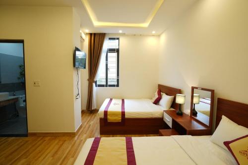 um quarto de hotel com duas camas e uma televisão em Sapphire Hotel Hue em Hue