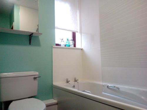 a bathroom with a toilet and a tub and a window at Silver Tides House in Greenock