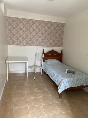 a bedroom with a bed and a table and a desk at Hostel Pigally in Goiânia