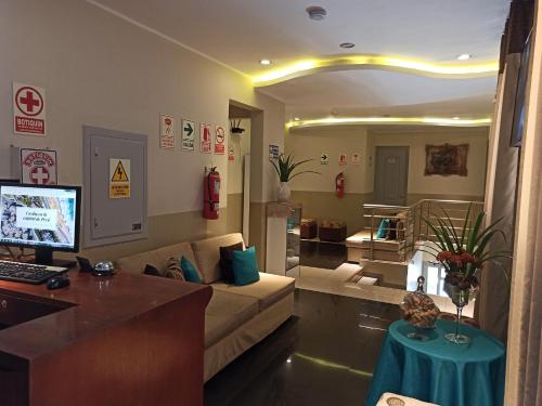 sala de estar con sofá y escritorio con ordenador en Hotel Brickell en Lima