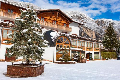 a ski lodge with a christmas tree in the snow at Hotel & Residence Montana in Fai della Paganella