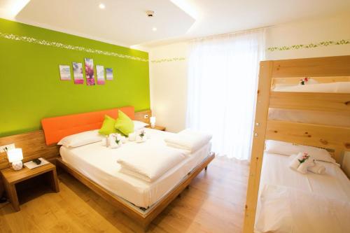 a bedroom with two beds and a green wall at Hotel & Residence Montana in Fai della Paganella