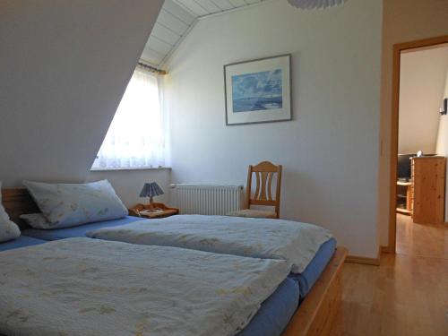 ein Schlafzimmer mit einem Bett, einem Stuhl und einem Fenster in der Unterkunft Haus Nordseemelodie,Wohnung 9  in Wittdün