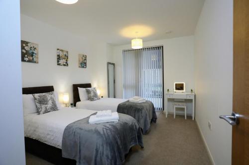 a hotel room with two beds and a desk at FW Haute Apartments at Queensbury, Ground Floor 2 Bedrooms and 2 Bathrooms with King or Twin beds with Front Porch and FREE WIFI and FREE PARKING in Wealdstone