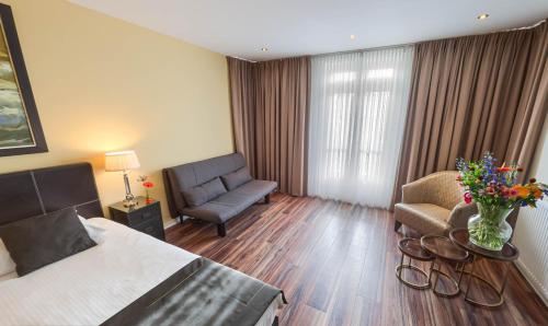 a hotel room with a bed and a couch and a chair at Boutique Hotel Chariot - Amsterdam Schiphol Airport in Aalsmeer
