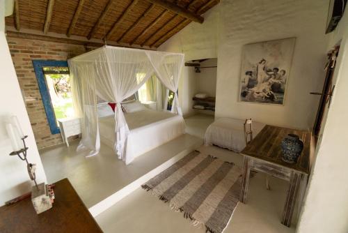 um quarto com uma cama com cortinas e uma mesa em Casarão Alto Mucugê em Arraial d'Ajuda