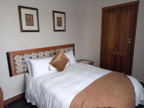 a bedroom with a white bed with a wooden headboard at Troas Boutique hotel in Vanderbijlpark