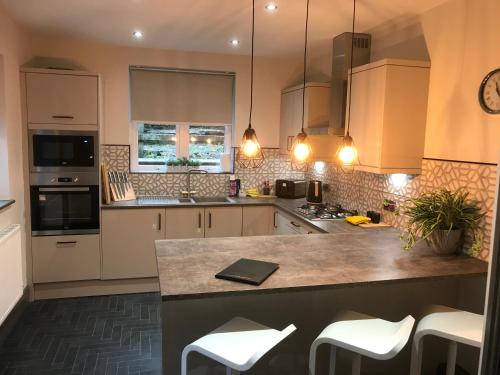 a kitchen with white cabinets and a counter with stools at North Lodge in Lancaster