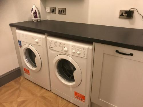a laundry room with two washing machines and a counter at North Lodge in Lancaster