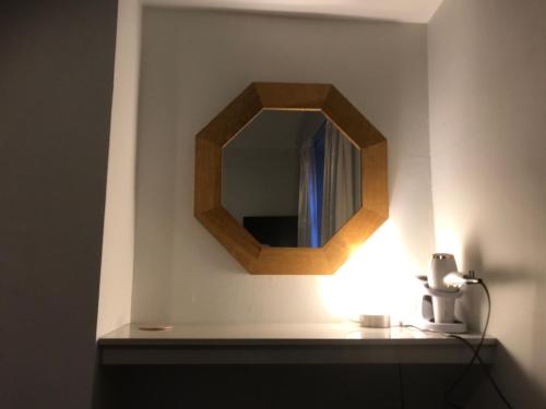a mirror on a wall with a light on a shelf at North Lodge in Lancaster
