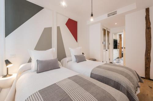 two beds in a room with white and gray at Apartamento Tirso en Madrid in Madrid